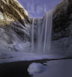 Scenic view of waterfall against sky during winter