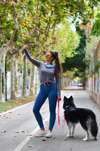 Full length of woman with dog on road