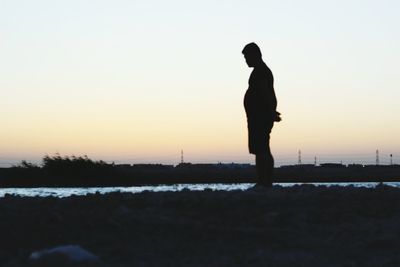 Silhouette man standing against clear sky during sunset