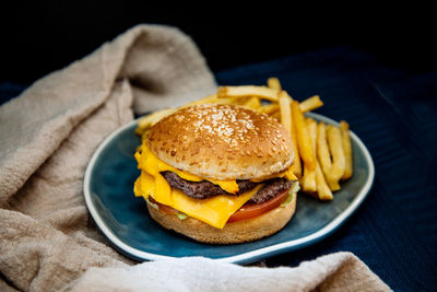 Close-up of burger in plate on table against black background