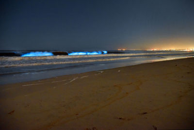 Scenic view of beach against sky at sunset