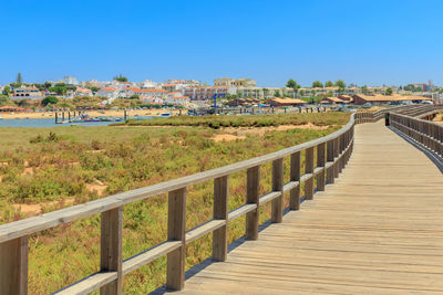 Footpath in town against clear blue sky