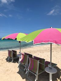 Lounge chairs and parasols on beach against sky