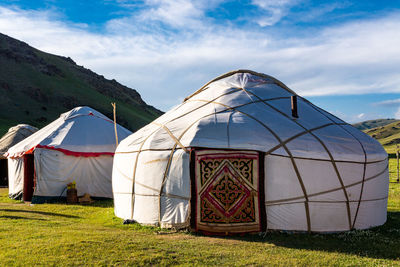 Tents on field against cloudy sky