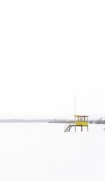 Lifeguard hut on snow covered landscape against clear sky