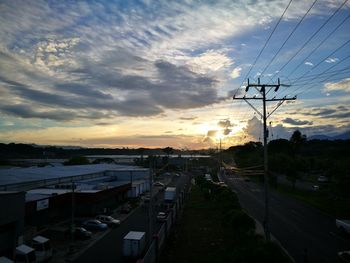 Road by city against sky during sunset