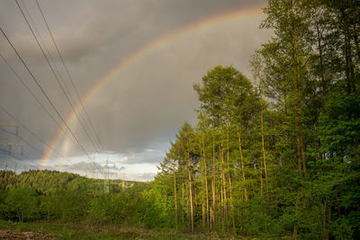 Scenic view of rainbow over trees on landscape against sky