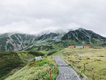 Road leading towards mountains against sky