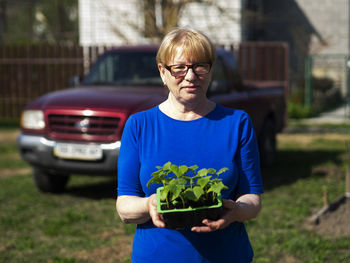 Mid adult woman standing against plants