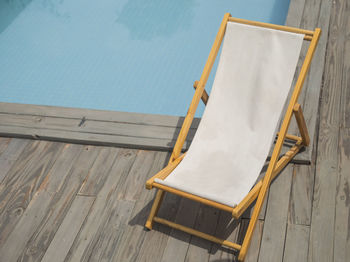 High angle view of empty lounge chair against swimming pool