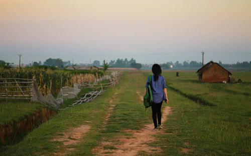 Woman on agricultural field against sky during sunset