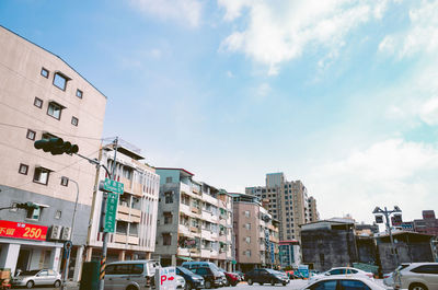 Cars on street by buildings against sky