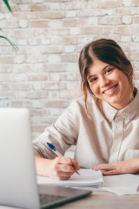 Portrait of smiling friends using laptop on table