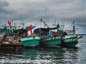 Boats moored at harbor against sky