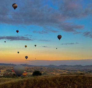 Hot air balloons flying over landscape against sky