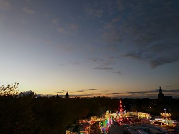 Illuminated city against sky at sunset