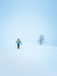 Man skiing on snow covered land against sky