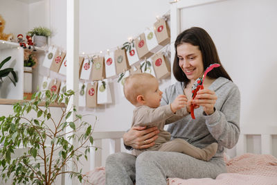 Mother with infant child having fun christmas advent calendar tasks and gifts. baby boy excited