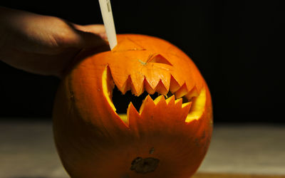 Cropped image of person carving pumpkin at table