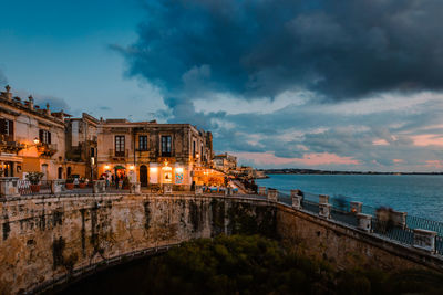 Buildings by sea against sky