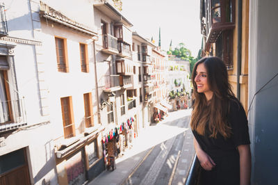 Side view of smiling young woman standing on balcony