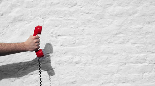 Person holding red umbrella against white wall