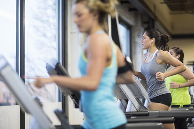 Women listening music while exercising on treadmills in gym