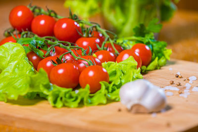 Fresh cherry tomatoes with green salad and garlic on a cutting board. healthy food concept. 