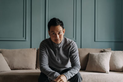 Young man sitting on sofa at home