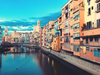 Buildings by canal against sky in city