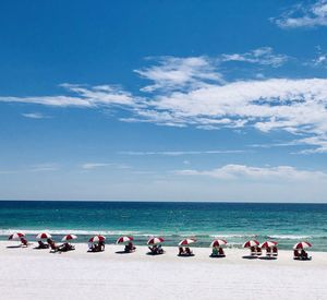 Group of people on beach against blue sky