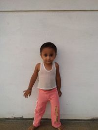 Portrait of baby boy standing against white wall