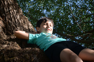 Smiling child standing on rock against trees