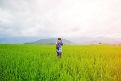 Woman standing on grassy field against sky