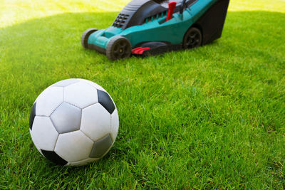Soccer ball and lawn mower on a field in the grass. close-up. grass care