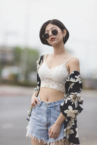 Portrait of sensuous young woman wearing sunglasses while standing on road
