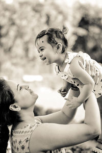 Mother holding cheerful daughter outdoors