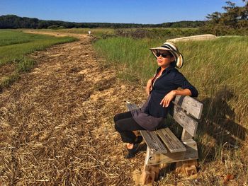 Portrait of woman sitting on grassy field against clear sky