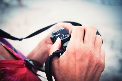 Close-up of man holding camera while standing outdoors