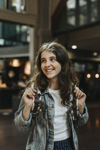 Happy girl with backpack standing at station