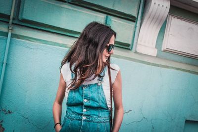 Woman wearing sunglasses while standing against wall