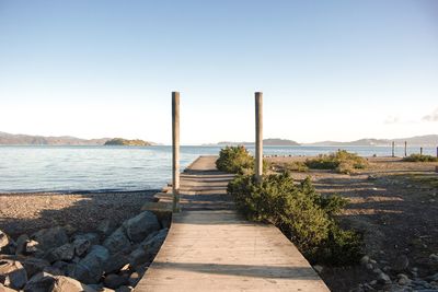 Footpath by sea against clear sky