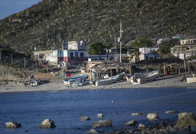 Scenic view of beach by buildings and mountains