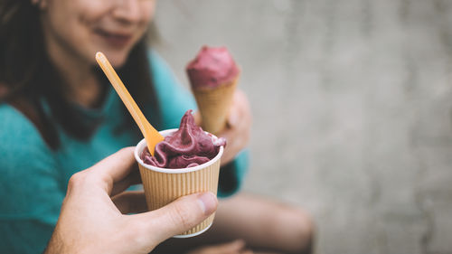 Cropped hand of man having ice cream with friend at footpath