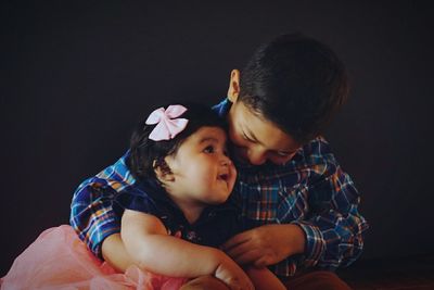 Smiling boy holding cute daughter at home