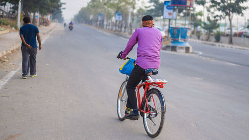 Rear view of man riding bicycle on road