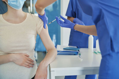 Midsection of doctor vaccinating patient at hospital