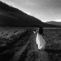 Rear view of woman with umbrella on landscape against sky