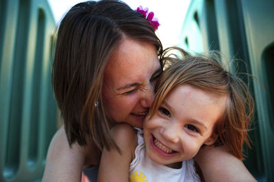 Close-up of cheerful mother and daughter sitting at park