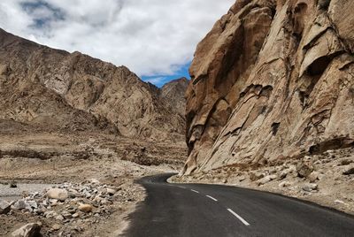 Road leading towards mountains against sky